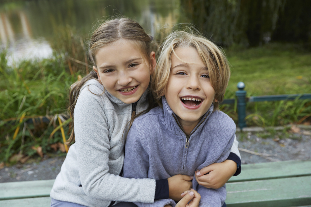 spaßiges Kinderpotrait, Kinder kuscheln miteinander, Kinder kucheln draußen in der Natur,