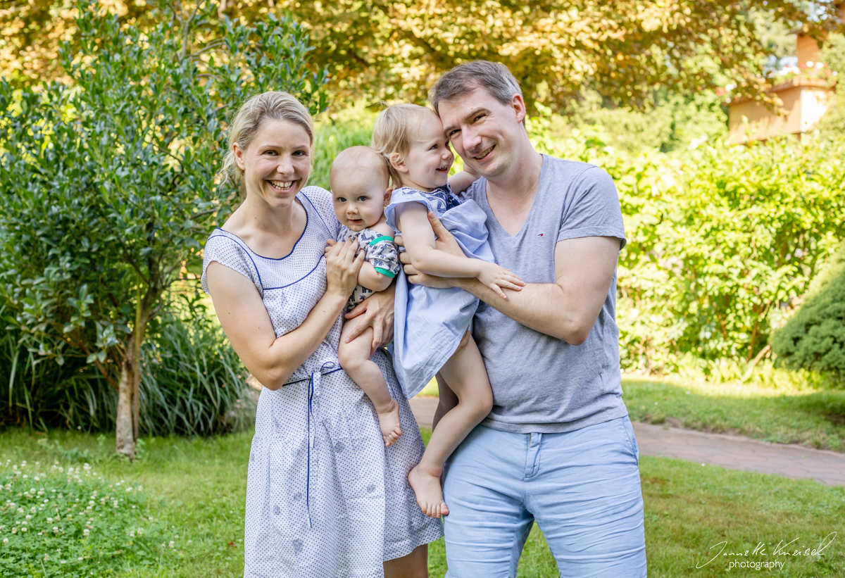 familienfoto im grünen mit sonnenstrahlen und glüklicher familie